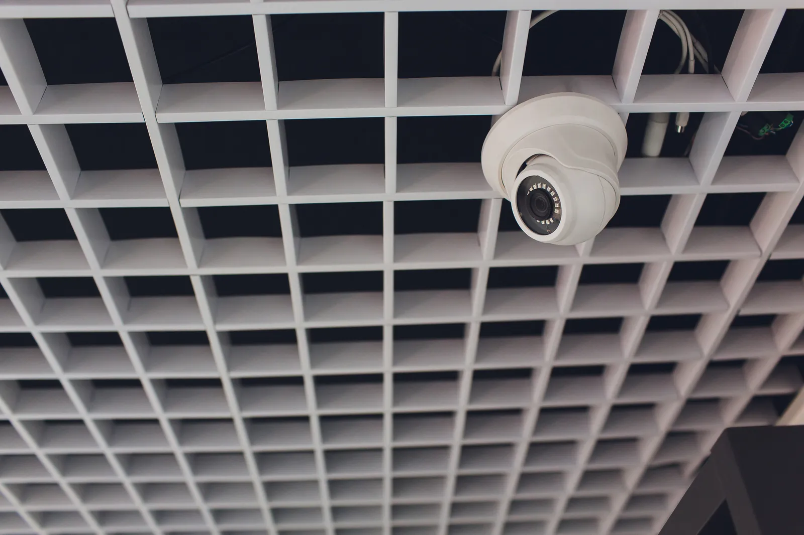 Cámara de seguridad y detector de movimiento instalados en techo modular de oficina corporativa