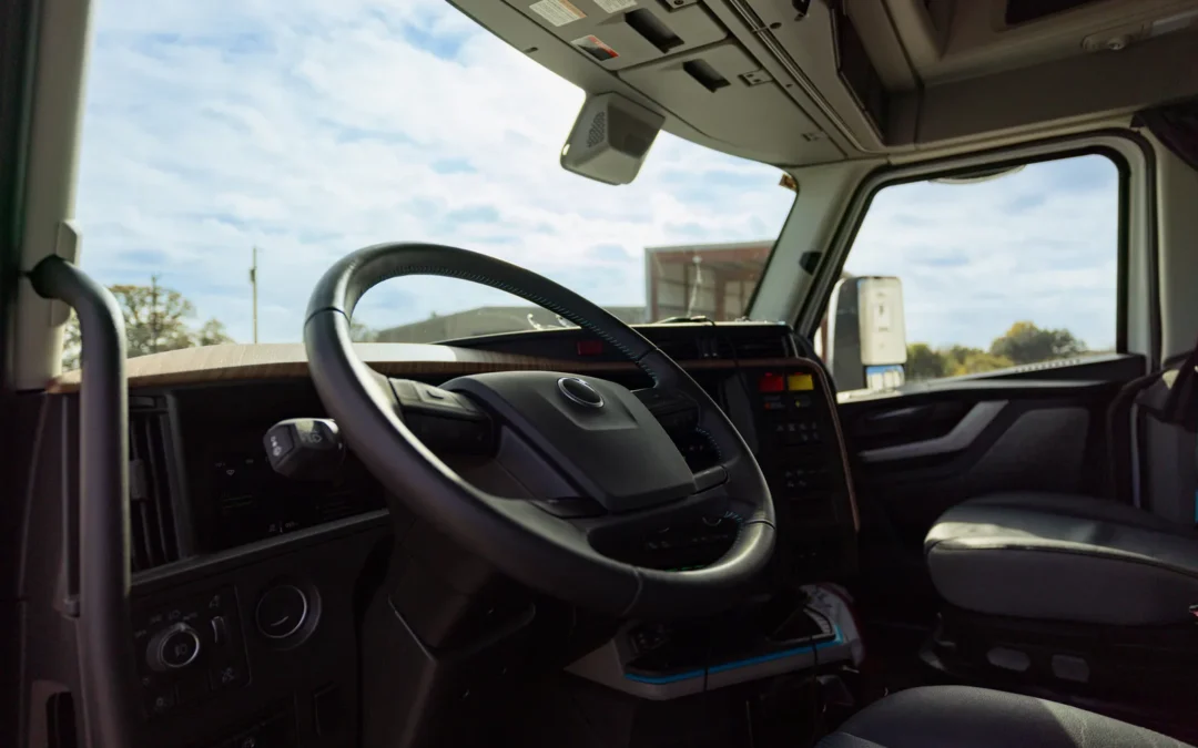 Interior moderno de cabina de camión comercial visto desde asiento del conductor con dashboard y ruta