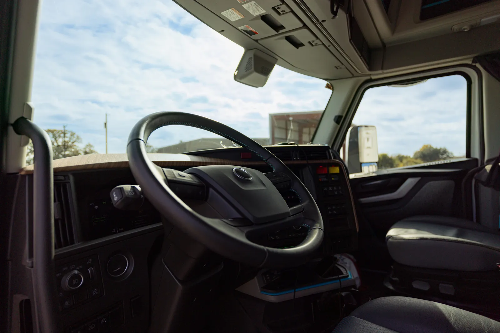 Interior moderno de cabina de camión comercial visto desde asiento del conductor con dashboard y ruta