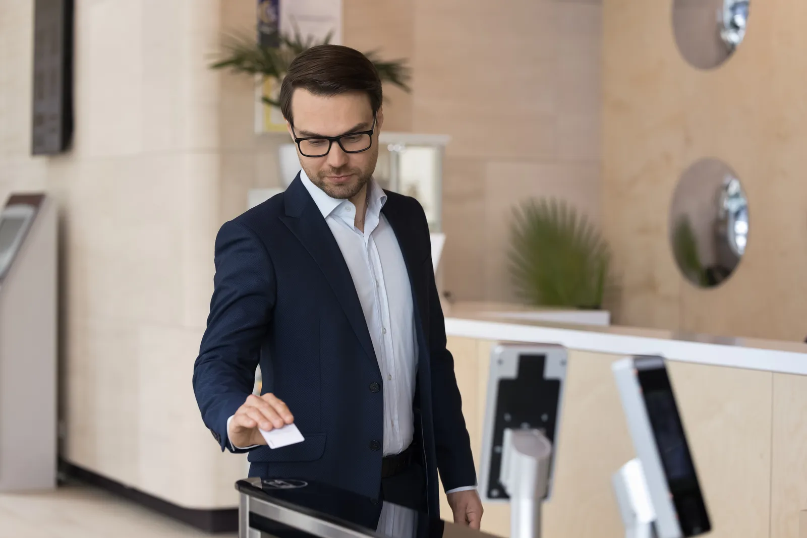 Ejecutivo usando tarjeta de acceso para abrir torniquete automático en oficina moderna