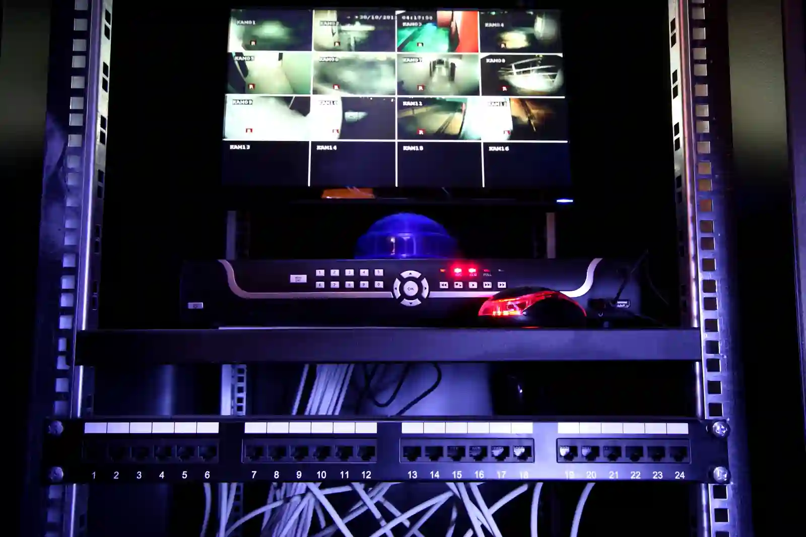 DVR antiguo y monitor con grilla de cámaras analógicas en sala técnica de torre corporativa