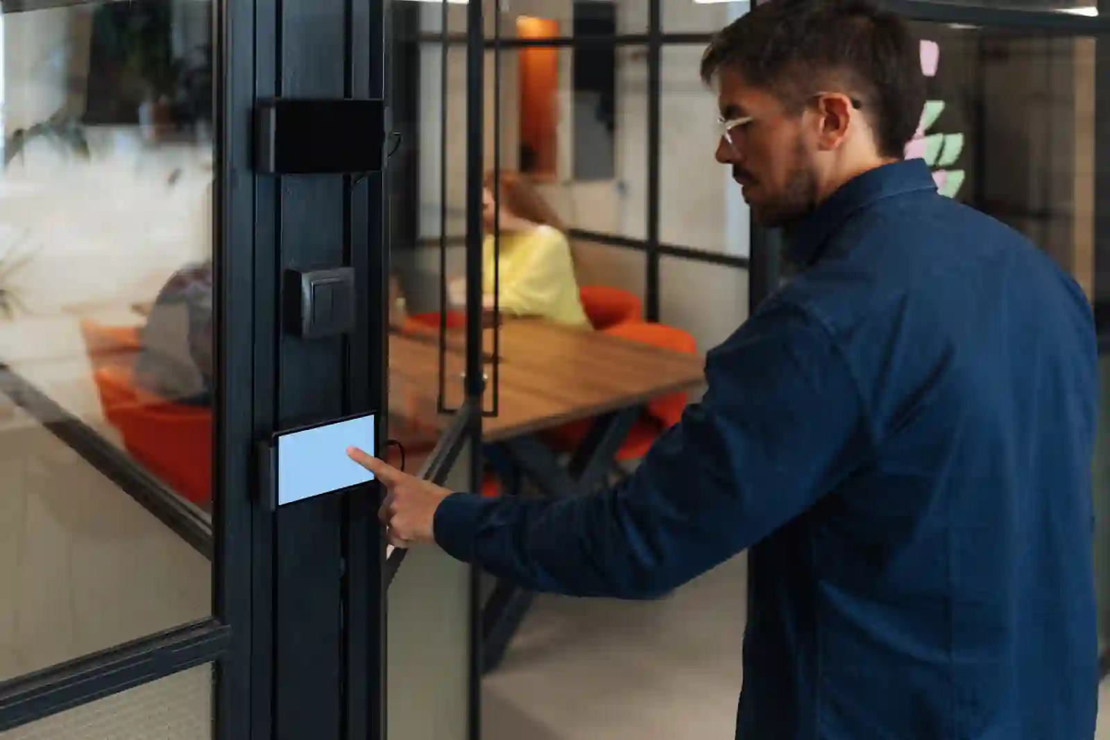 Trabajador de oficina usando panel táctil de control de acceso en oficina corporativa moderna