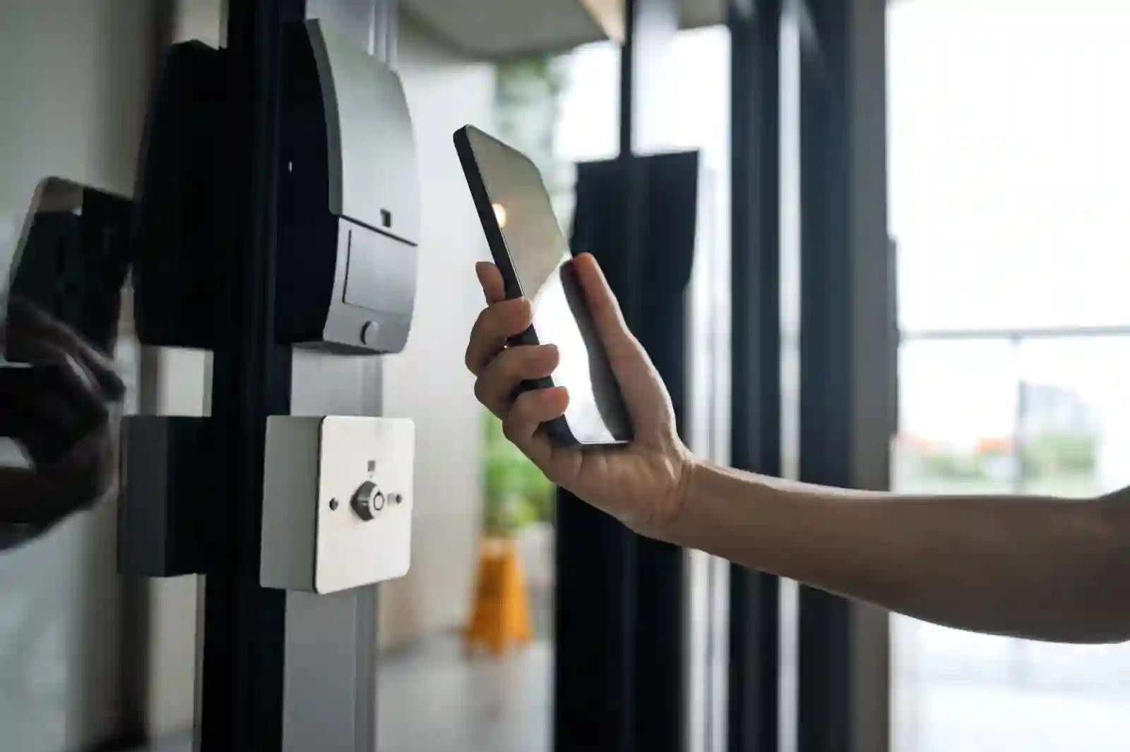 Persona usando smartphone para abrir puerta con tecnología NFC en oficina corporativa