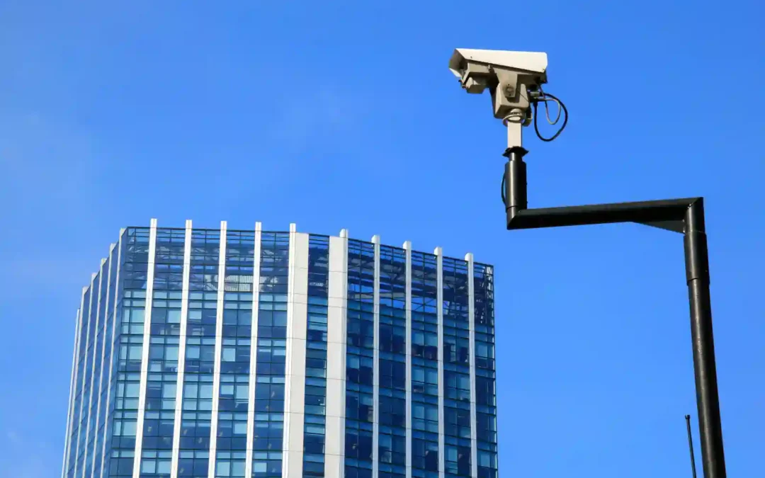 Cámara CCTV de seguridad apuntando sobre un edificio corporativo de oficinas con cielo despejado