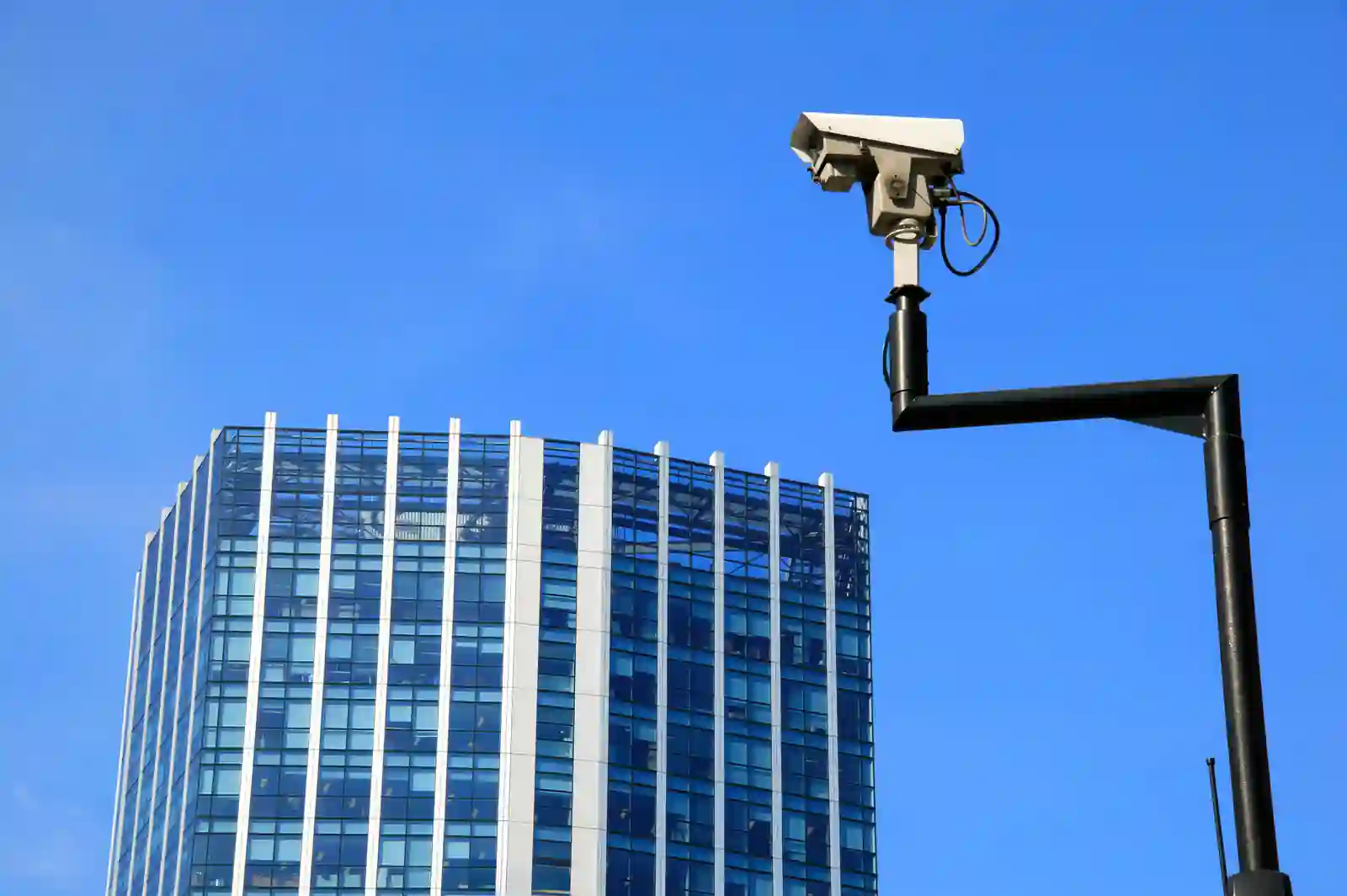 Cámara CCTV de seguridad apuntando sobre un edificio corporativo de oficinas con cielo despejado