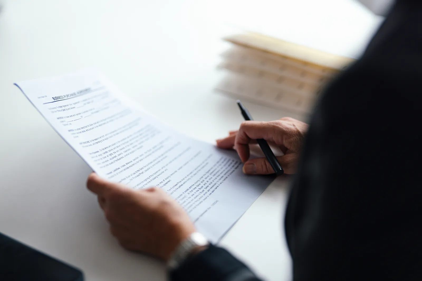 Manos profesionales con bolígrafo revisando un documento de contrato de servicio