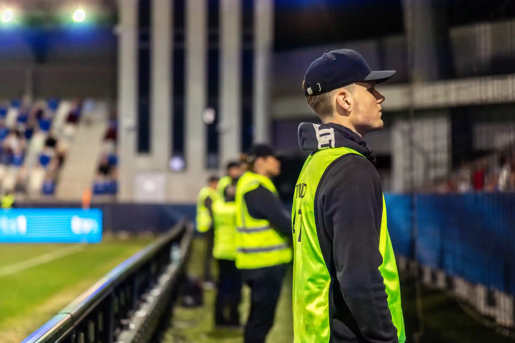 Personal de seguridad con chaleco fluorescente en un evento deportivo nocturno