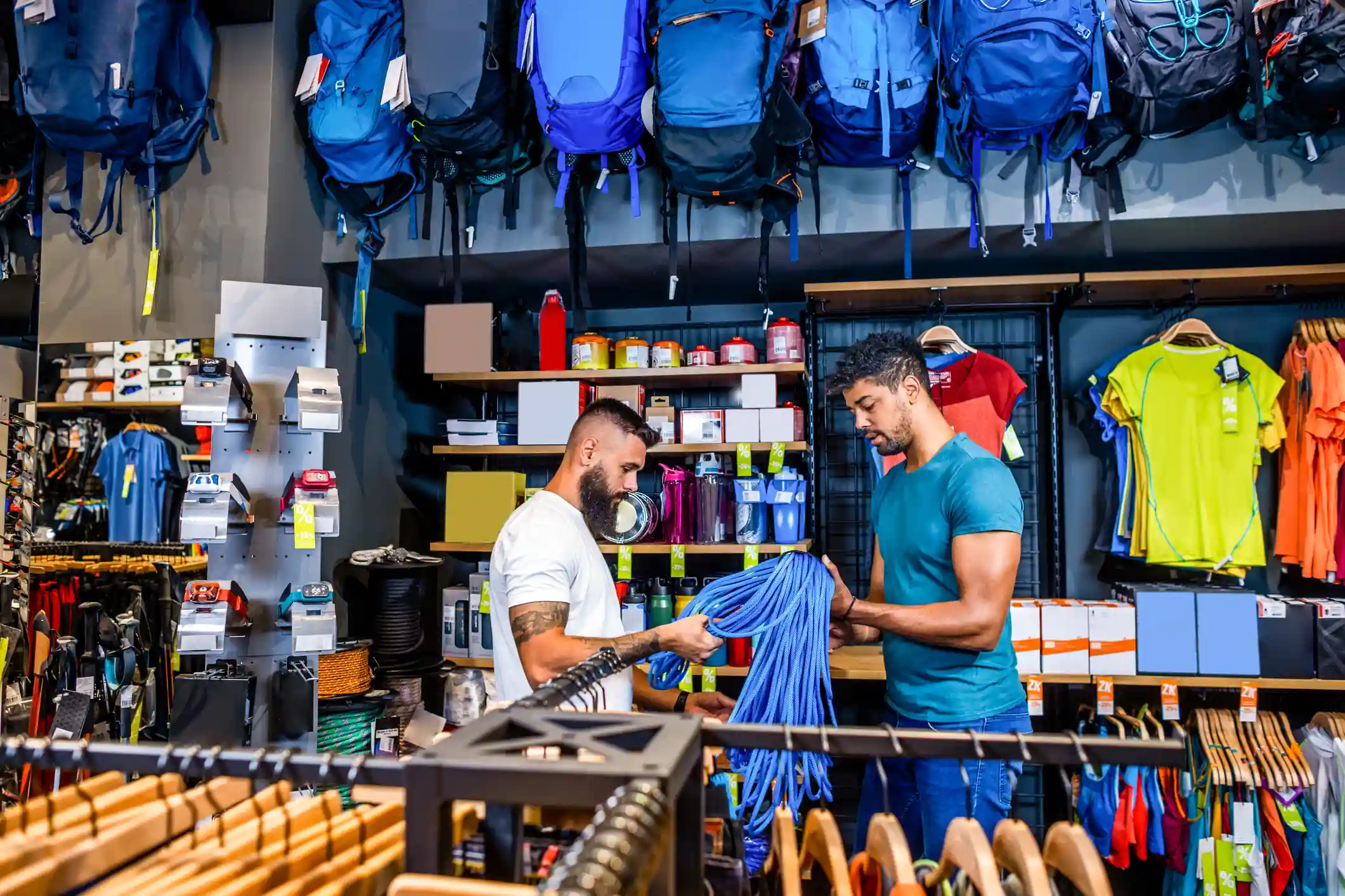 Dos clientes mirando productos dentro de una tienda deportiva con mochilas y accesorios