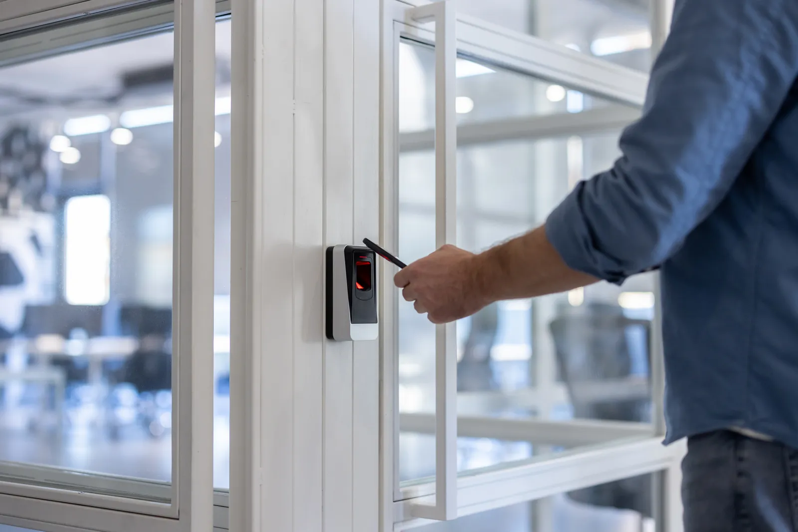 Empleado acercando su tag al lector de control de acceso en una puerta de oficina