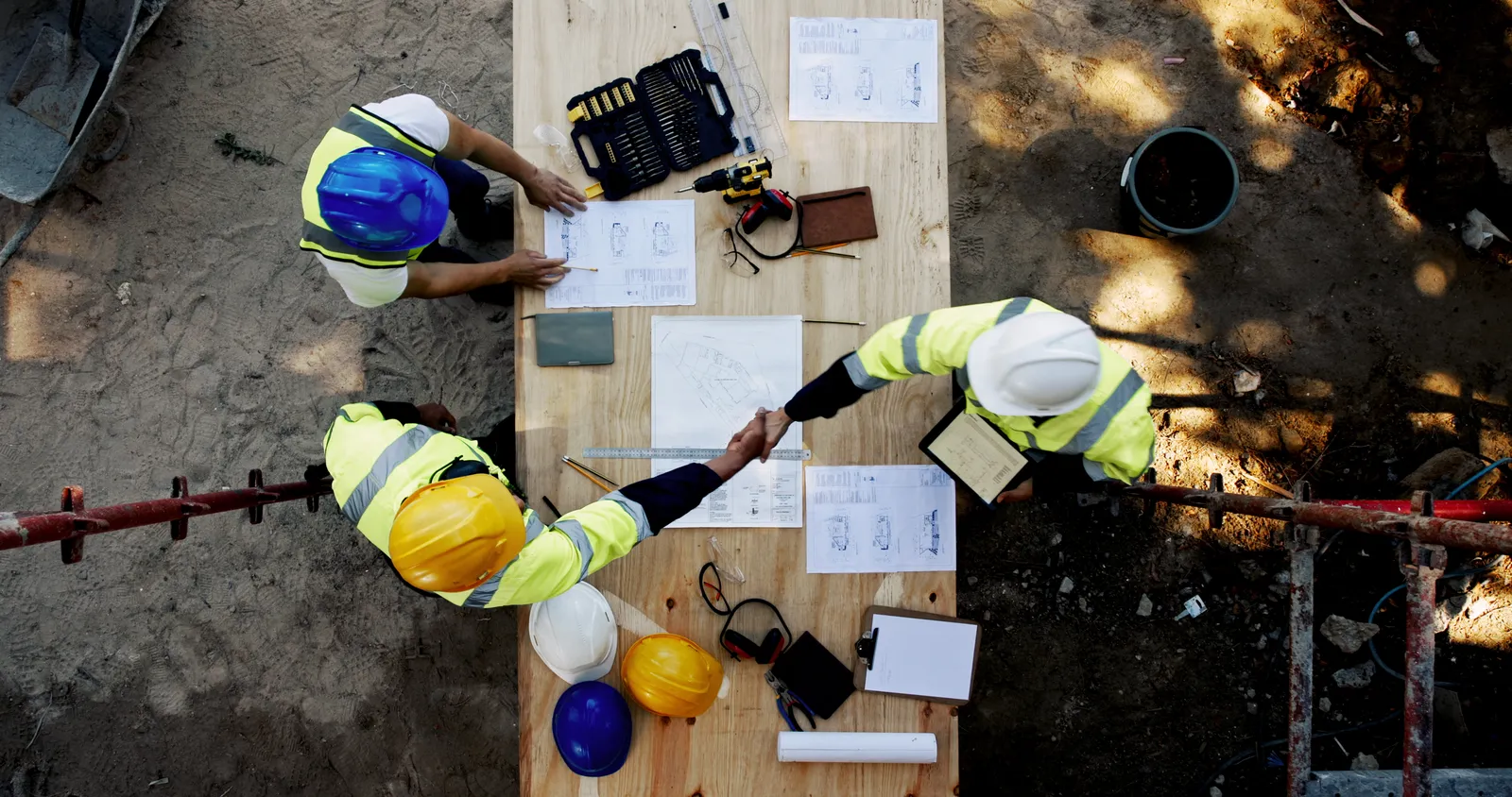 Supervisores y trabajadores revisando planillas y planos sobre una mesa de obra