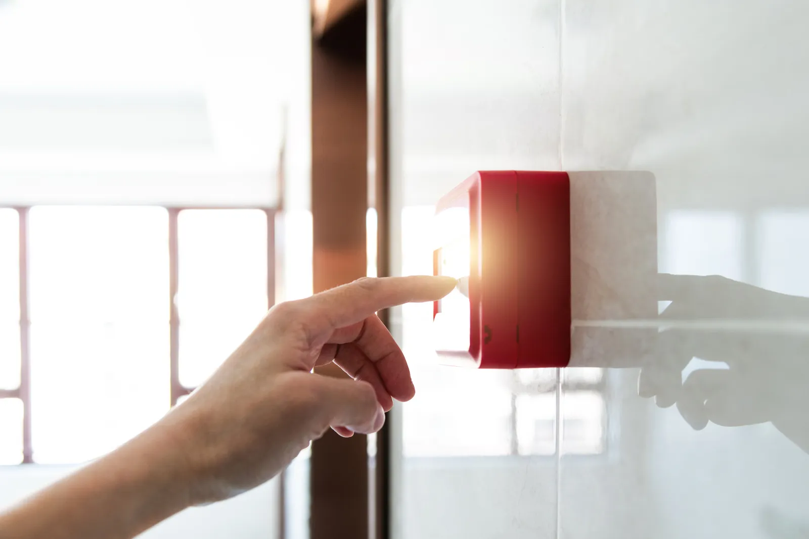 Mano activando el pulsador de una alarma sin monitoreo, el kit aislado que solo suena