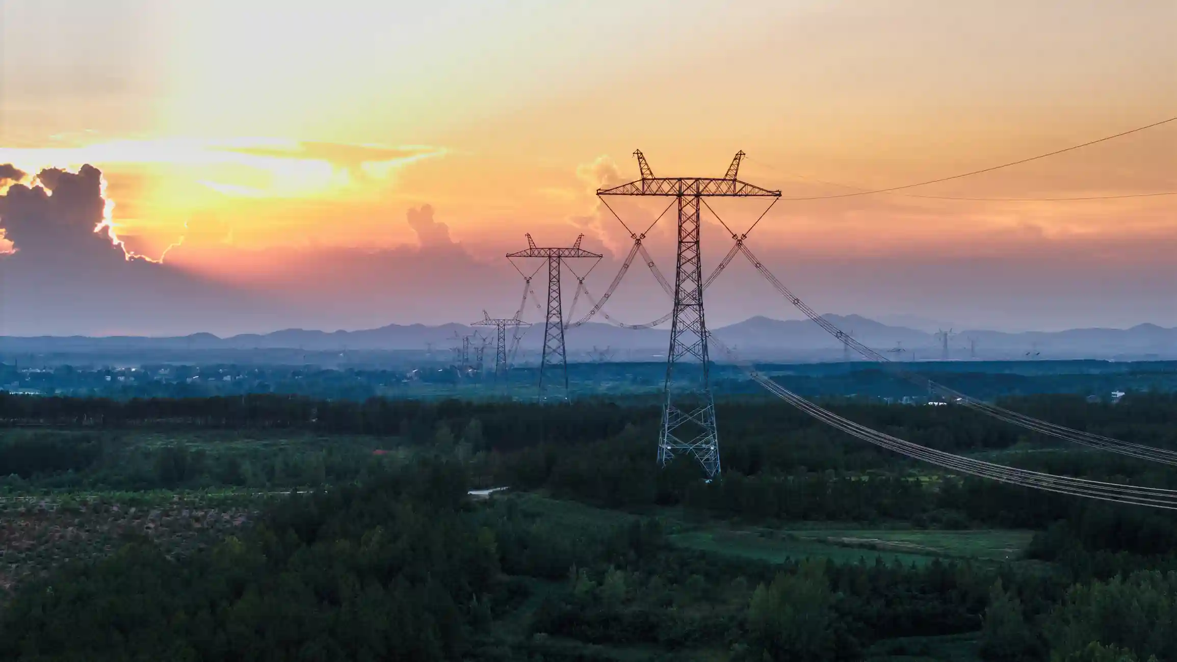 Torre de línea de alta tensión al atardecer con el tendido eléctrico