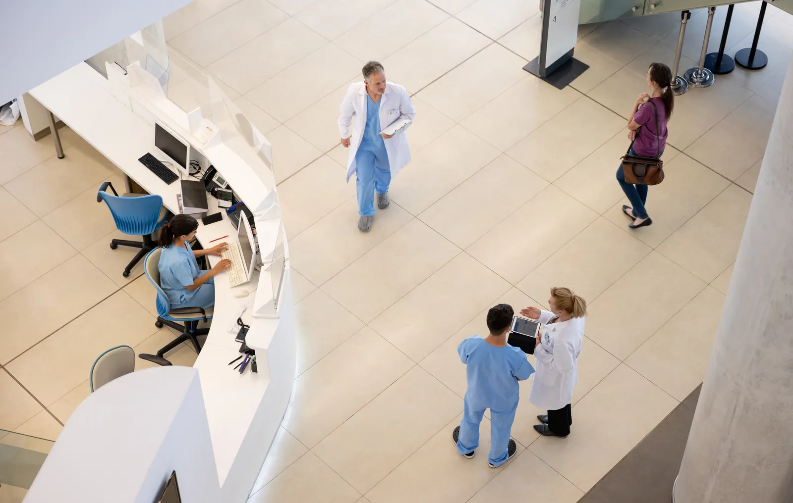 Vista aérea del hall de un hospital con personal de salud circulando y Vista aérea del hall de un hospital con personal de salud circulando y el mostrador de recepción