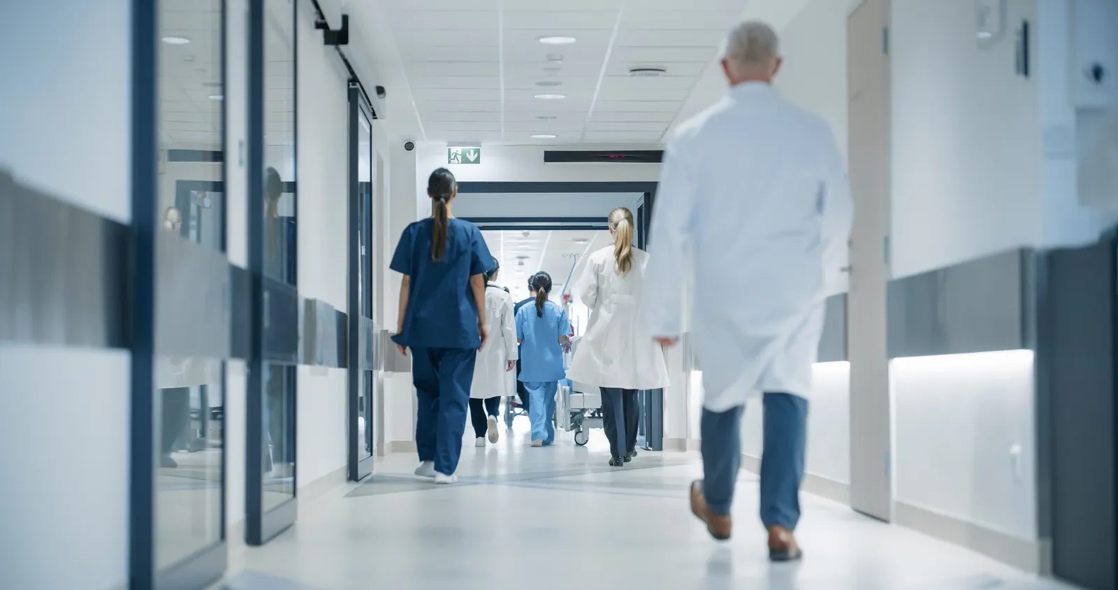 Equipo de salud caminando por el pasillo de un hospital hacia la puerta de un sector restringido