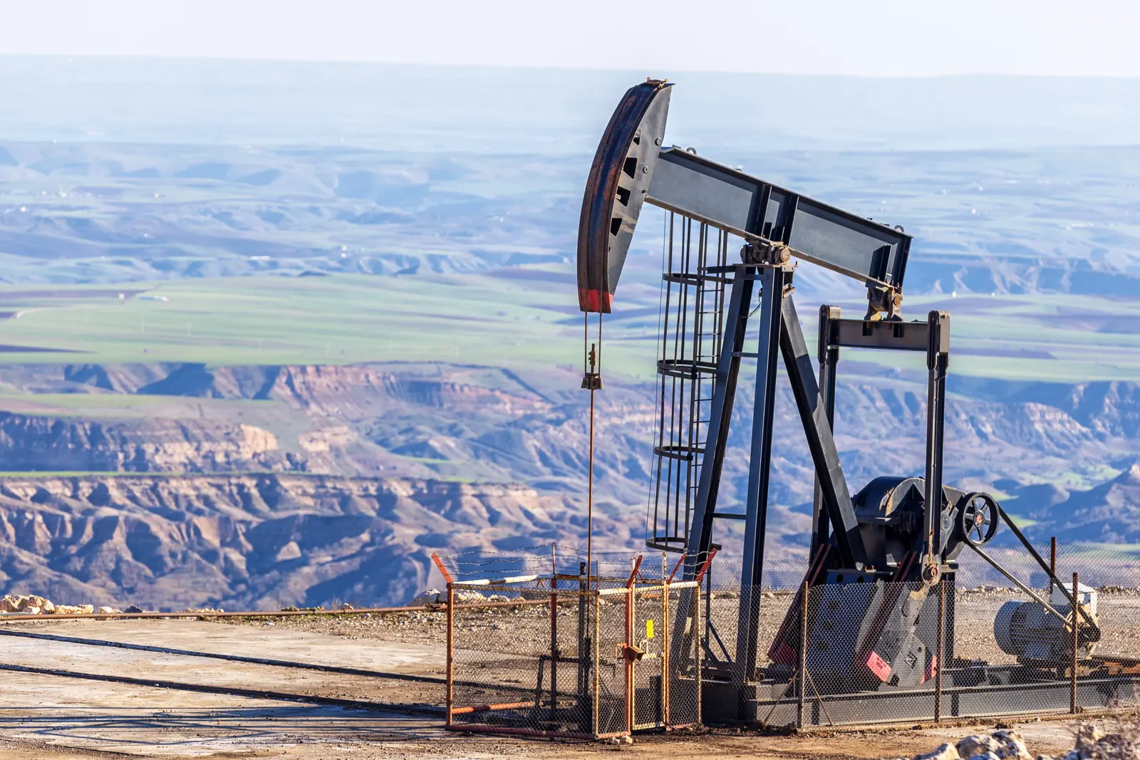 Equipo de bombeo mecánico de petróleo en una locación sobre un paisaje árido