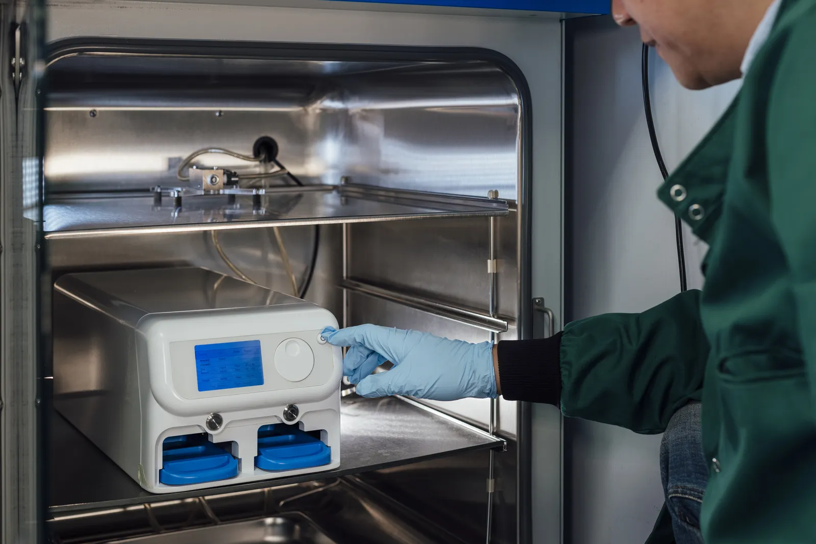 Técnico con guantes operando un equipo dentro de una cámara de estabilidad de laboratorio