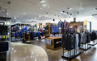 Interior de un local de indumentaria de una cadena, con percheros y exhibidores